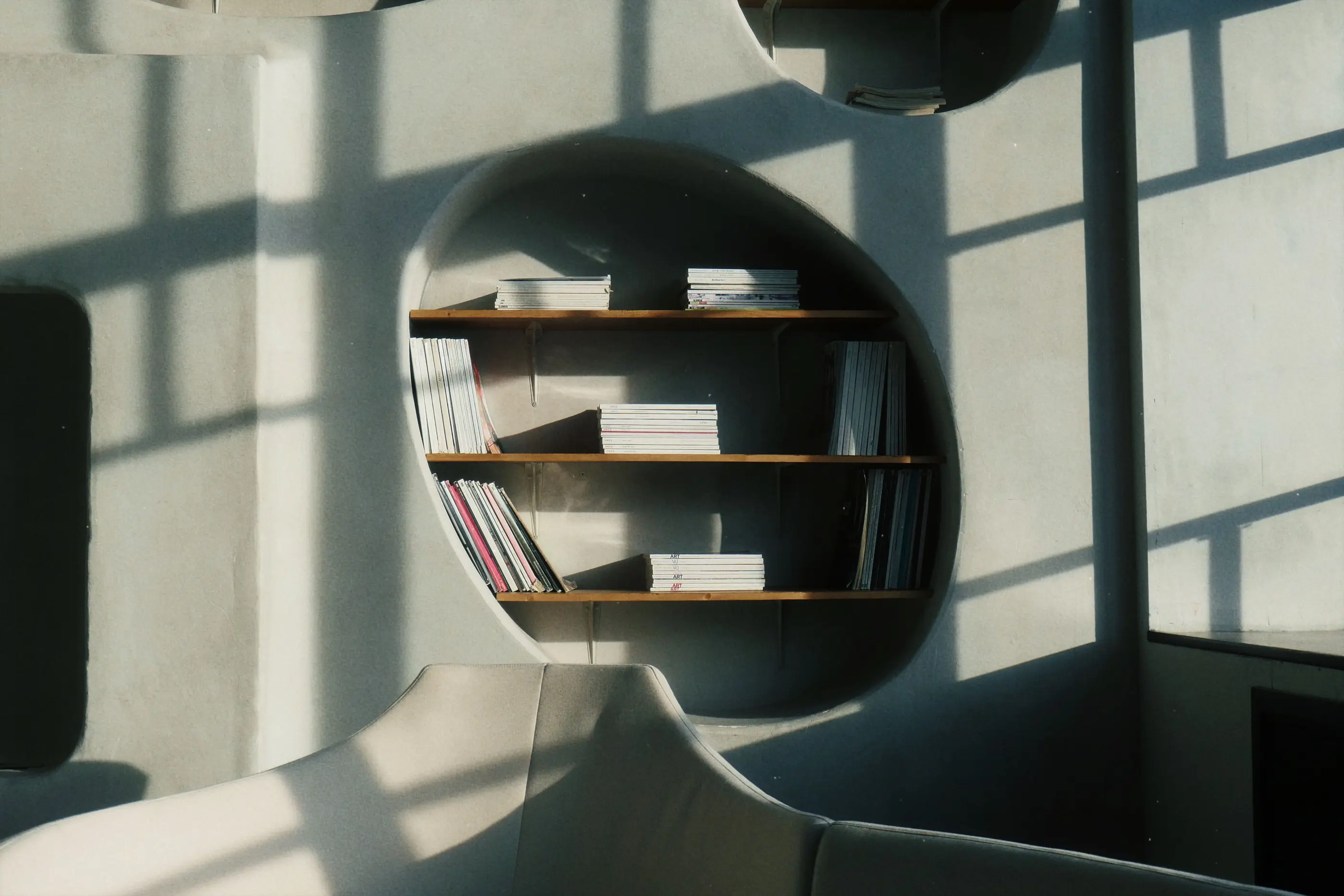 Verda: a curved timber-lined interior, raked daylight across the shelving